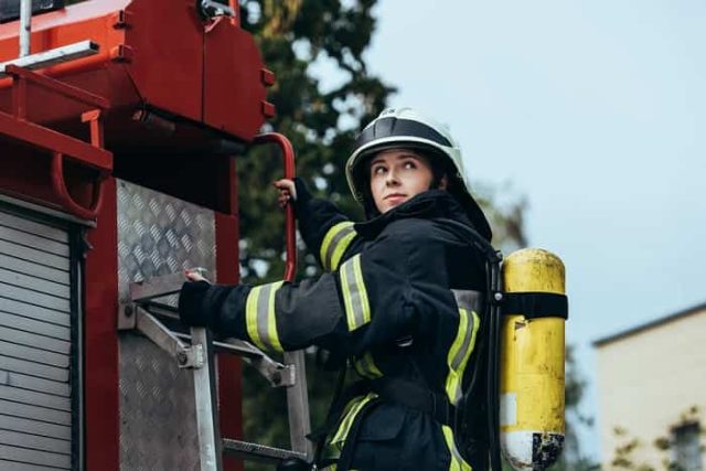 Γυναίκα Πυροσβέστης στο πίσω μέρος πυροσβεστικού οχήματος